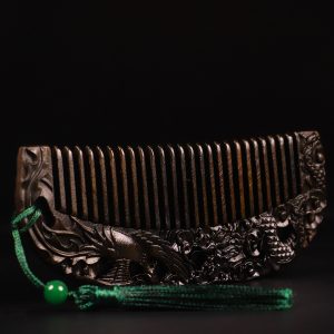 A natural old material black agarwood comb with carvings of dragons and phoenixes symbolizing good fortune. There is a certificate.